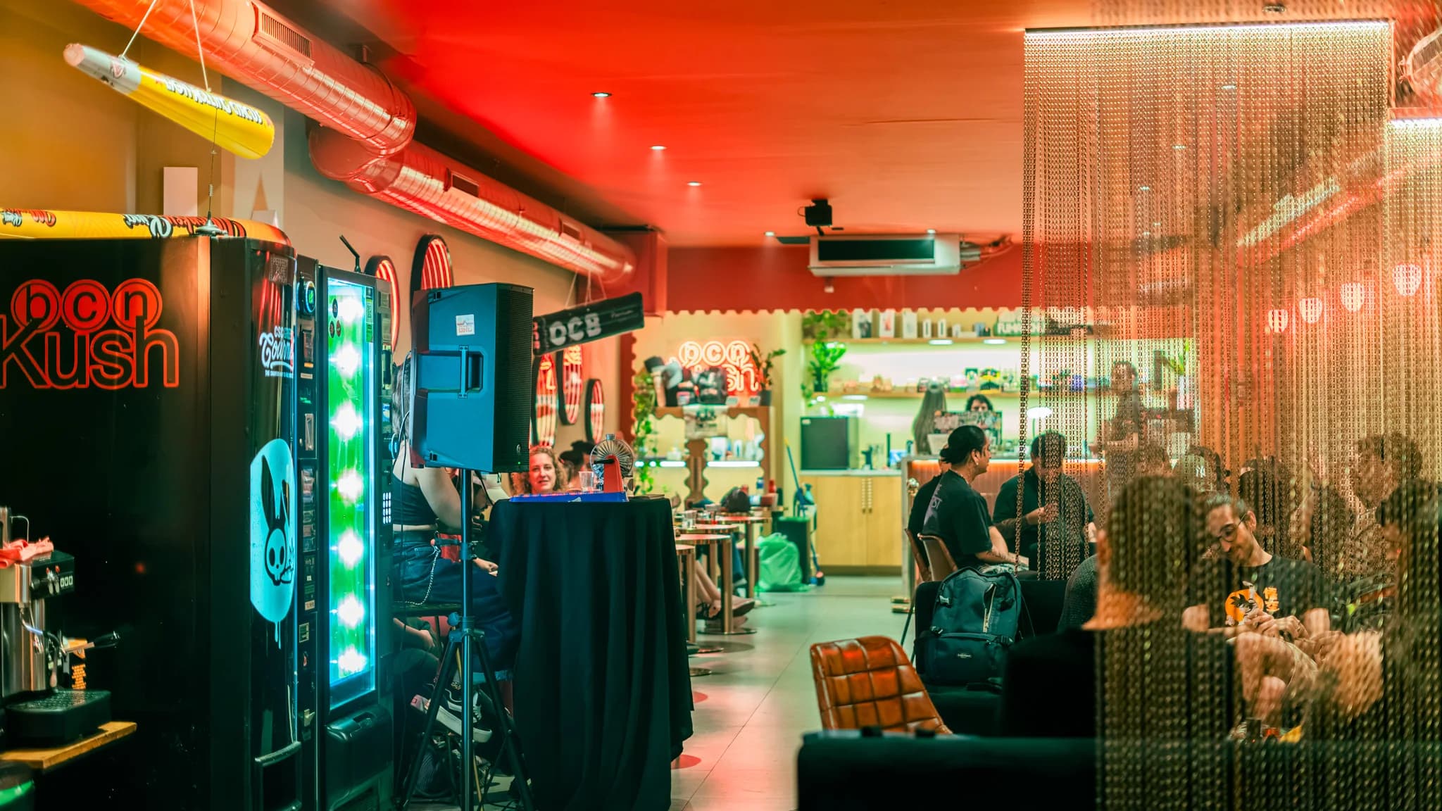 Zona de juegos de Bcn Kush Weed Club con máquina arcade y neón rojo