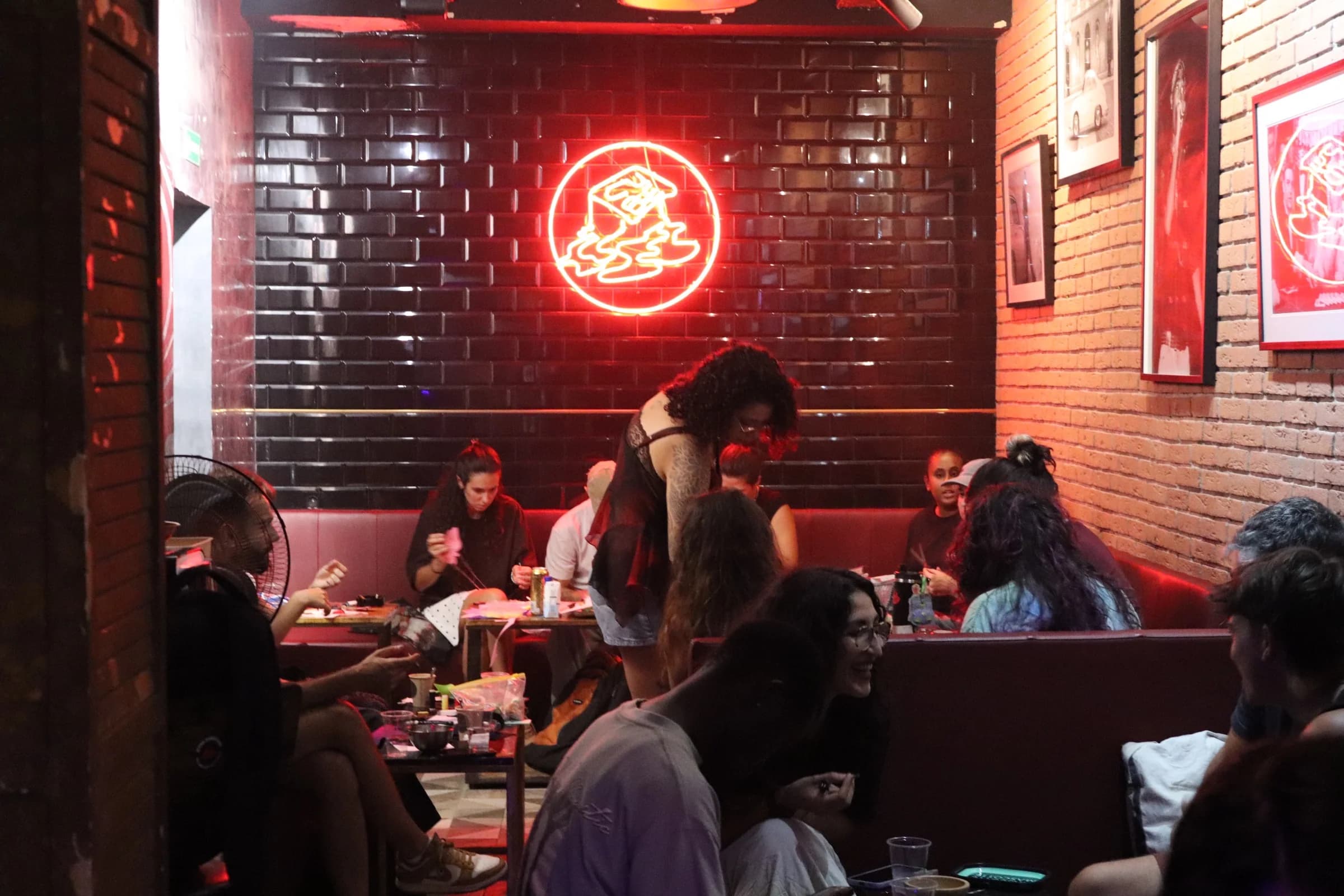 Members chatting on the sofas at Cube Weed Club by the neon logo