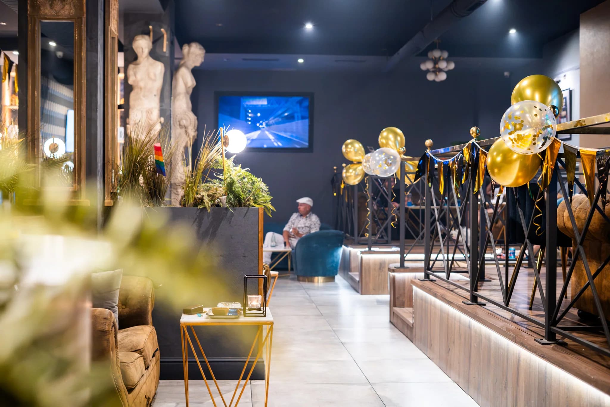 Sala principal de High Class Weed Club, club cannábico en Poblenou (Barcelona), con estatua, cuadros dorados y globos