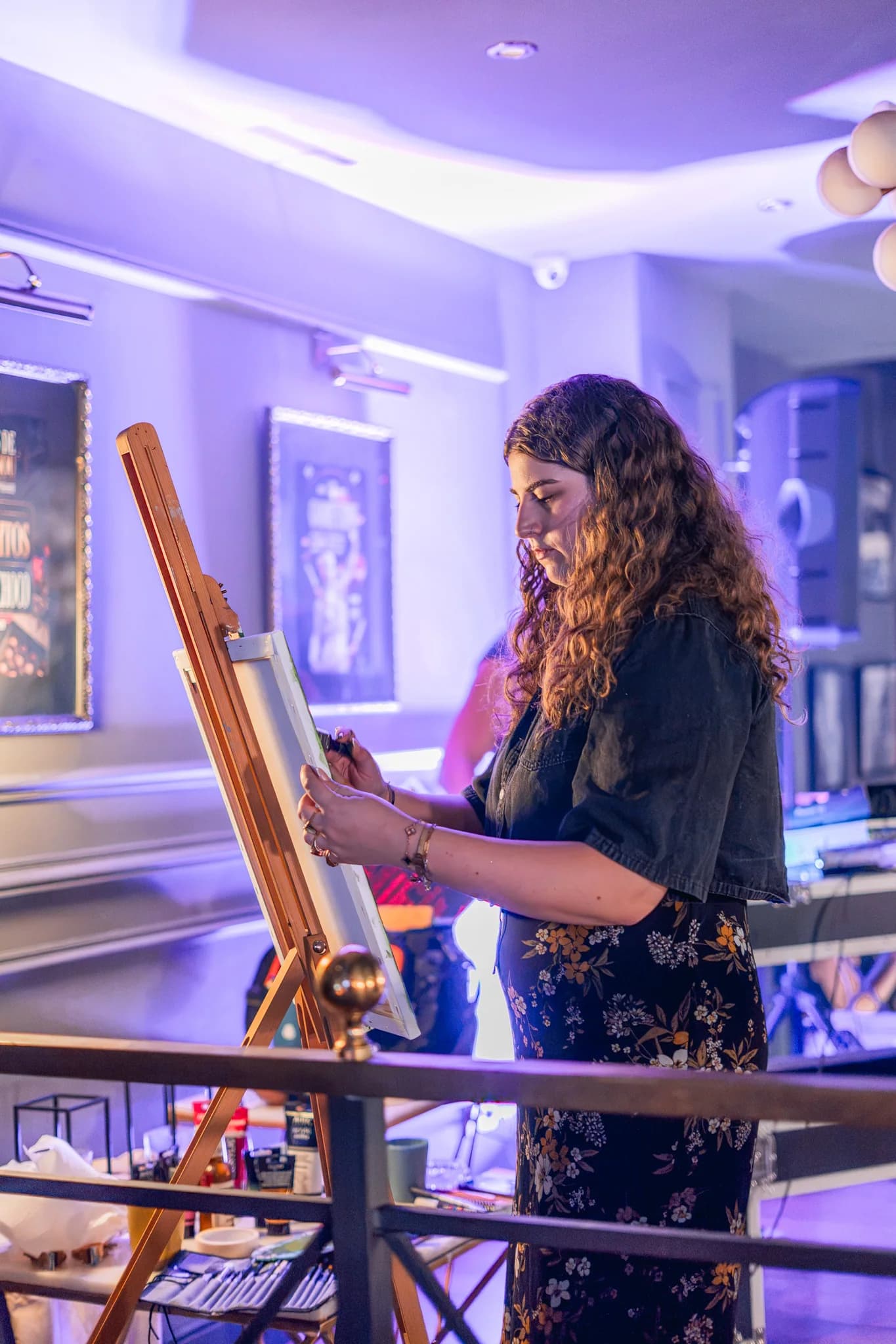 Taller de pintura en High Class Weed Club: una socia pinta en un caballete bajo luz violeta