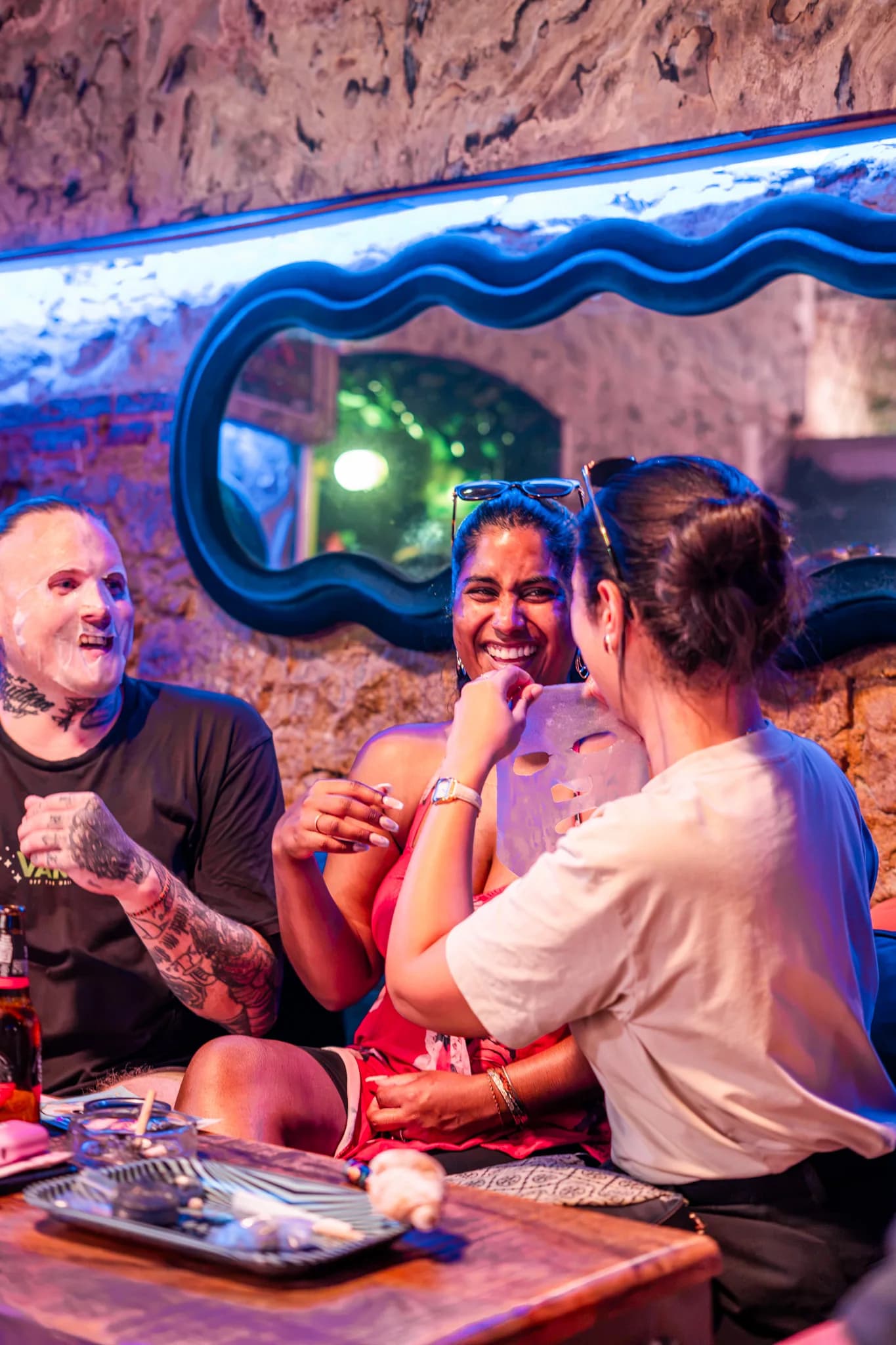 Tres socios charlando bajo el espejo con neón de The Cut Weed Club