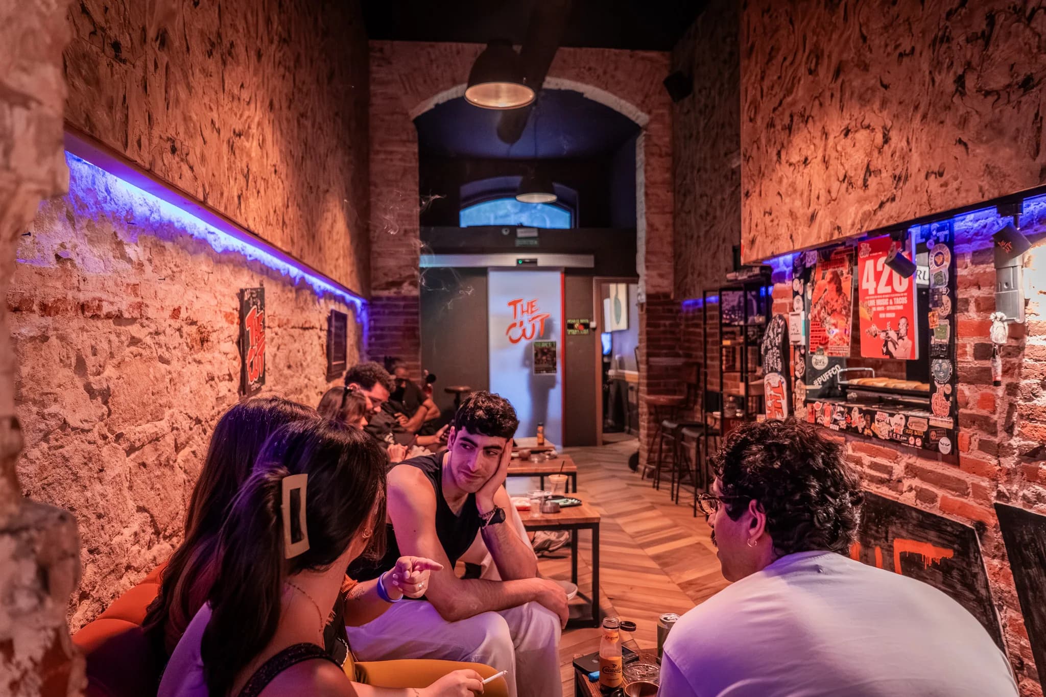 Zona lounge de The Cut Weed Club con luz de neón azul y rosa